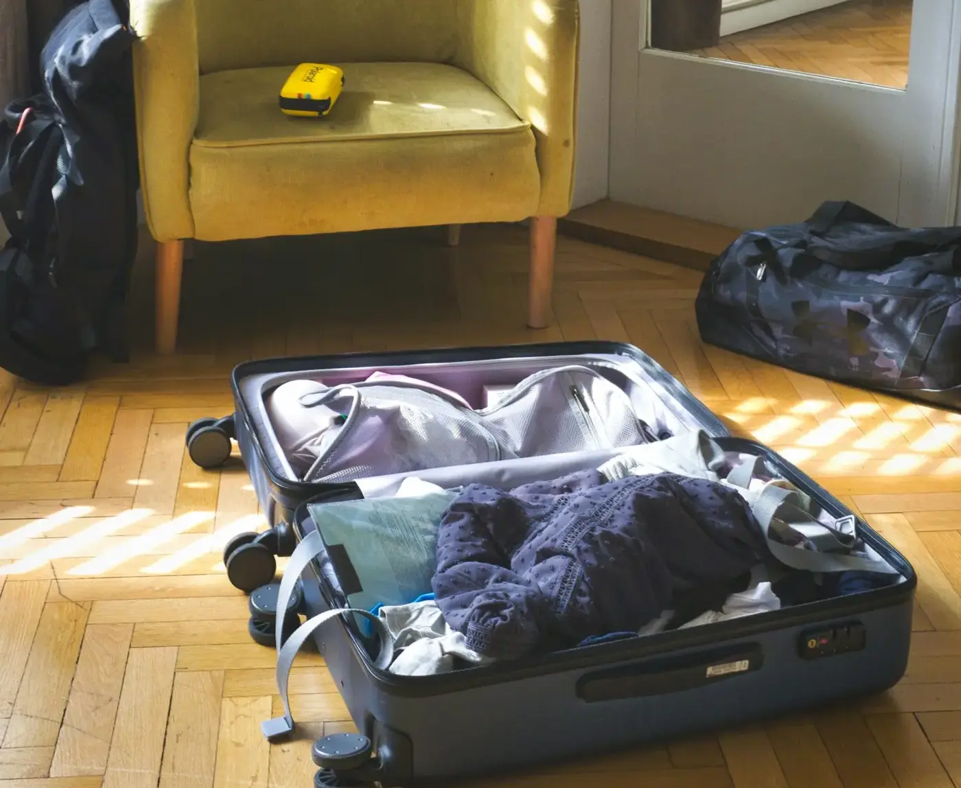 Half-packed suitcase open on a sunlit wooden floor